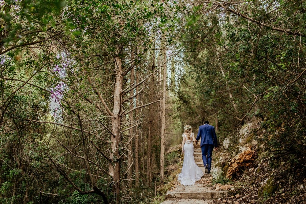 Bride and groom walking up stairs through a forest