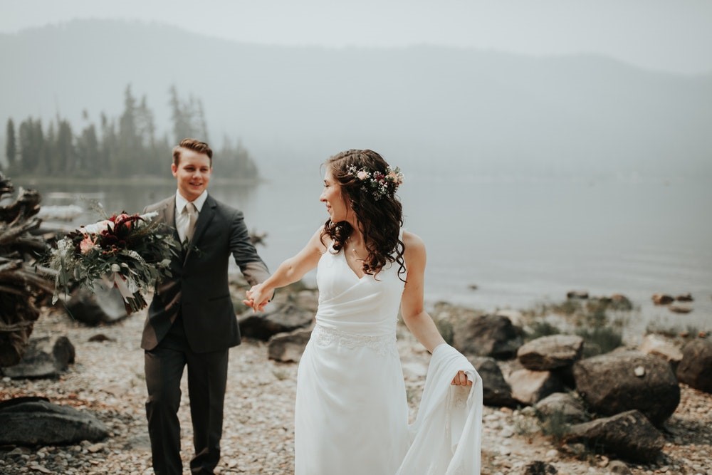Bride and groom walking lake's edge