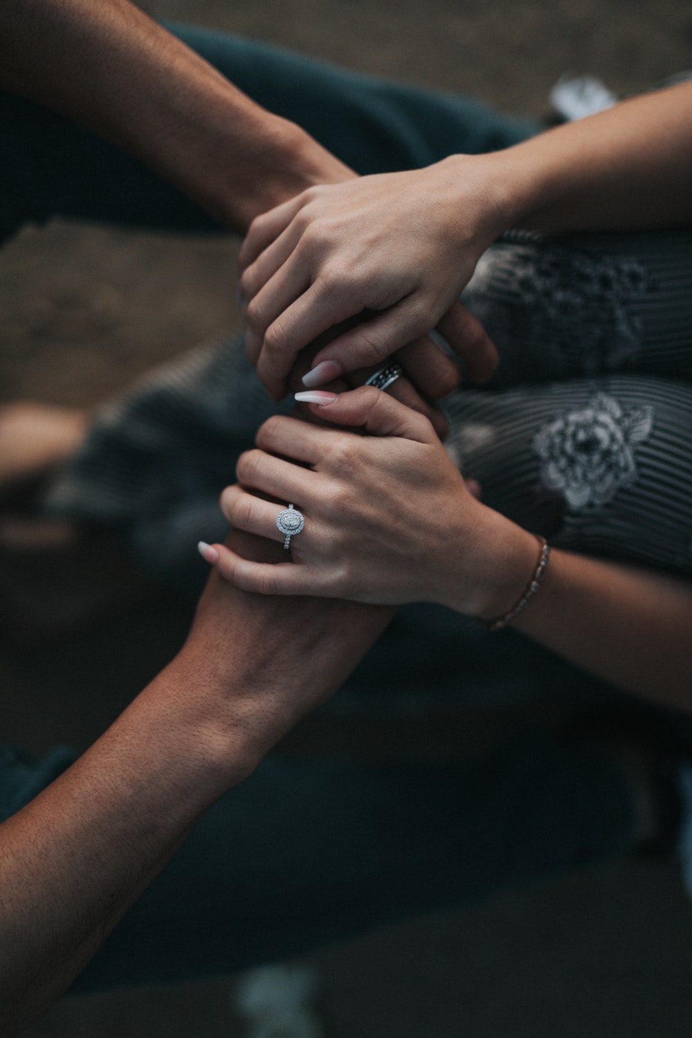 couples holding hand with engagement ring