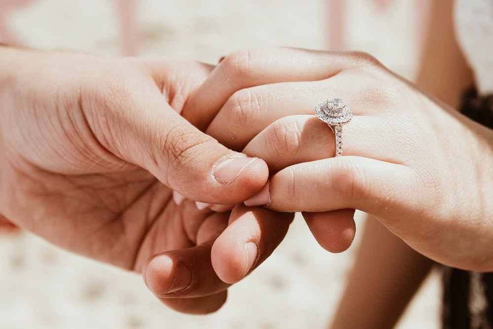 Man holding woman's hand with diamond ring