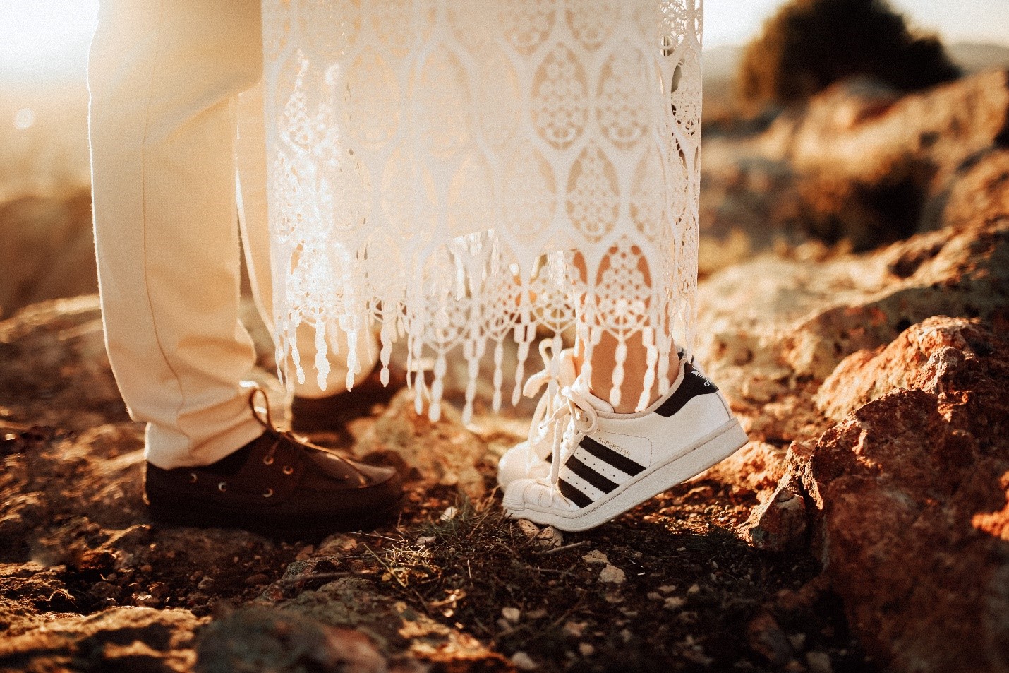 Close-up of man and woman's shoes on rocky ground