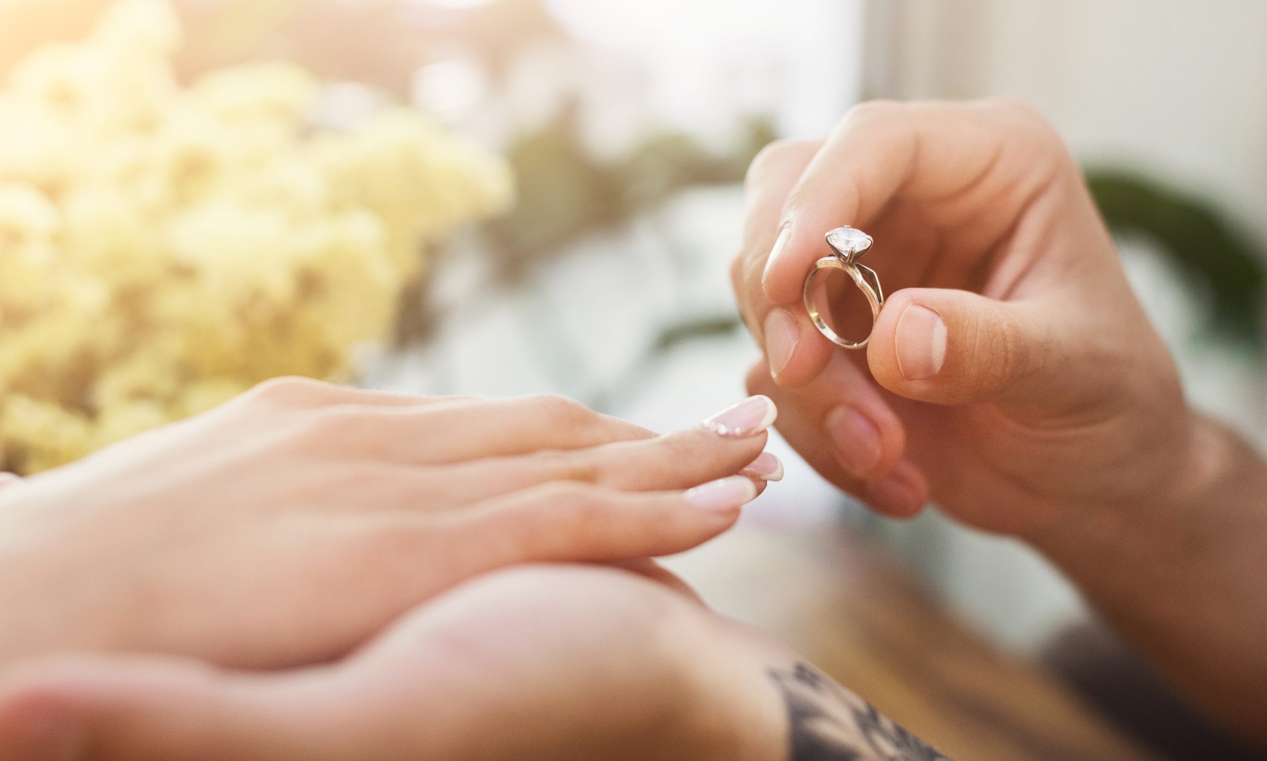 A man putting an engagement ring on a woman's finger