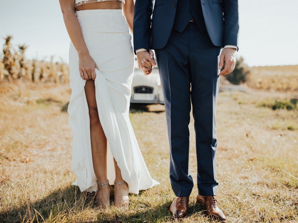 Bottom half of couple standing off-road on grass