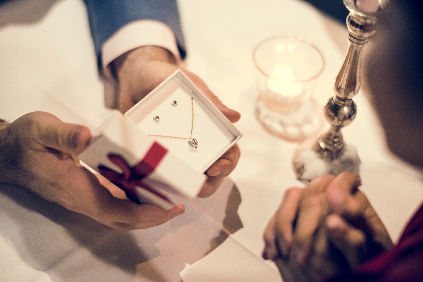 Man presenting diamond necklace and earring set in jewelry box to woman