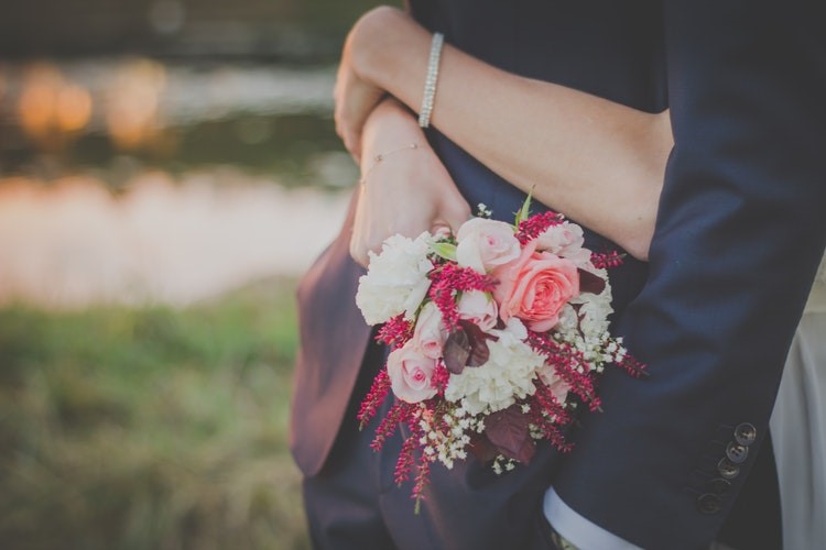 Woman hugging man, holding bouquet of flowers