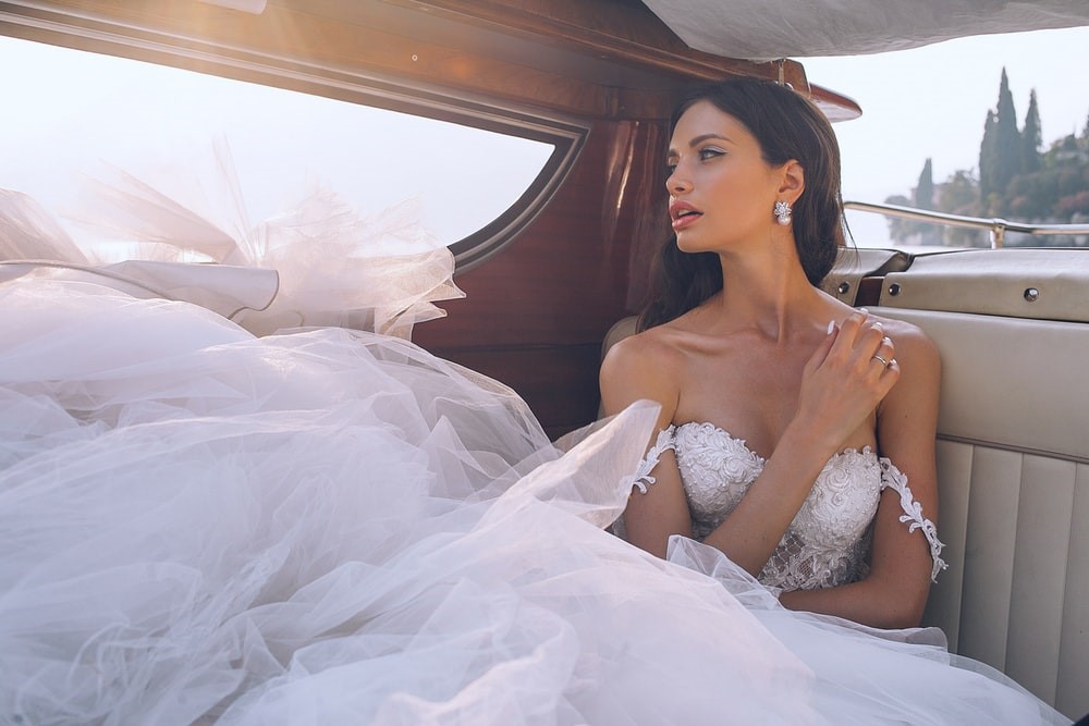 Woman in wedding dress in back seat of car