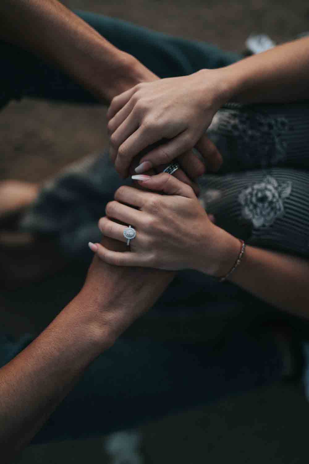 couples holding hands with engagement rings
