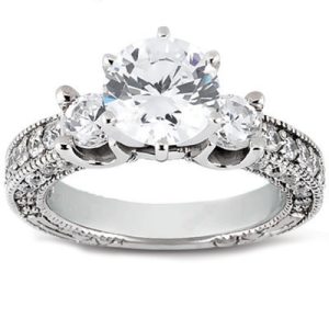 A three-stone engagement ring features a large central diamond flanked by two smaller diamonds on a textured silver band.