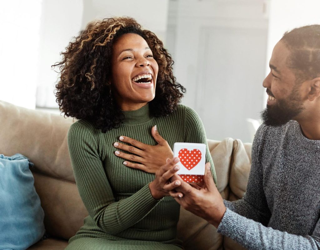 A happy woman receiving a small giftbox from her partner